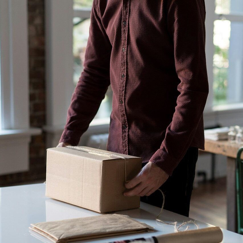 person holding cardboard box on table